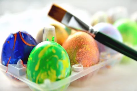 Colored eggs in a transparent box and an art brush Stock Photos