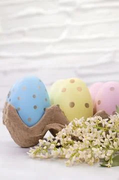 Colored eggs with white flowers on table. Easter. Copy space Stock Photos