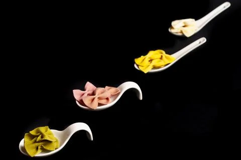 Colored farfalle paste in a white ceramic spoon 写真素材