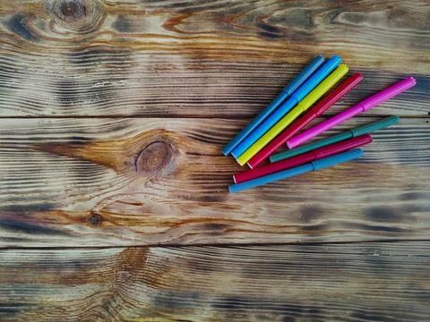 Colored felt-tip pens on a background of burnt wood Stock Photos