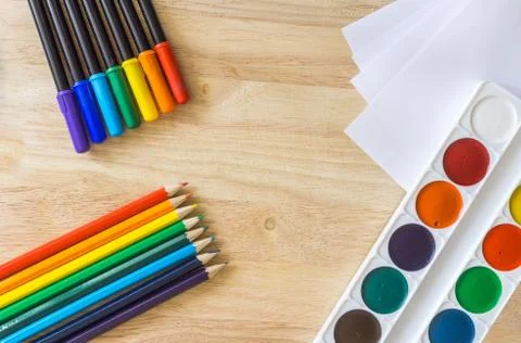Colored felt-tip pens, lying like rainbow colored pencils, white paper and wa Stock Photos