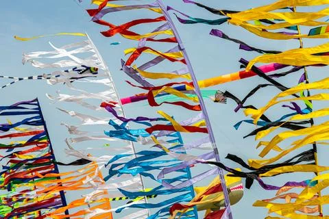 Colored flags against the blue sky with white clouds on holidays Stock Photos
