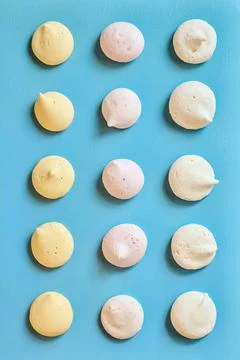 Colored fruit meringues lying in rows on a blue background Stock Photos