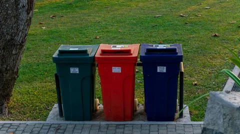 Colored garbage containers lined up in Galle fort park, green for organic stu Stock Photos