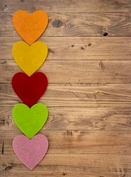 Colored hearts in a row down on a walnut wood background. Concept of St. Vale Stock Photos