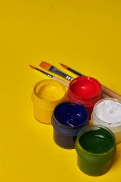 Colored jars of paint on a yellow background Stock Photos