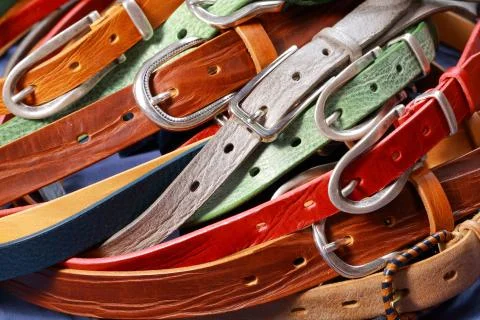 Colored leather straps on a white background. Leather belts with metal buckles. Stock Photos