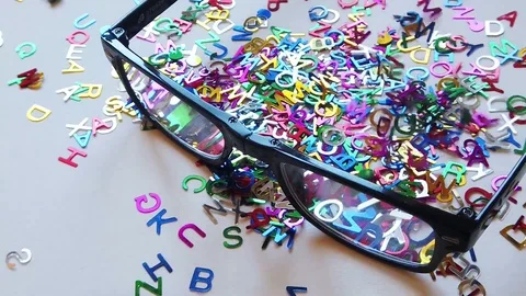 Colored letters falling over eyeglasses Video stock 124894684