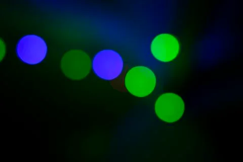 Colored light flashes in green and blue tones on black background Stock Photos