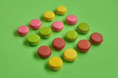 Colored macaron or macaroon, sweet meringue-based confection on green background Fotos Stock