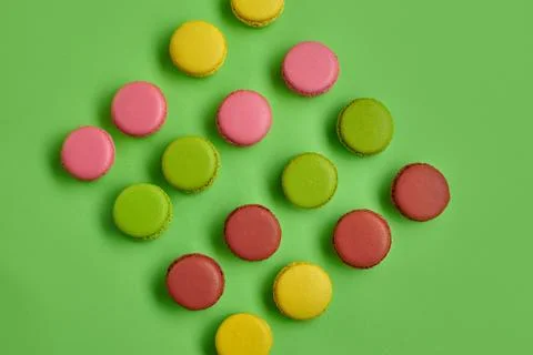 Colored macaron or macaroon, sweet meringue-based confection on green background Fotos Stock