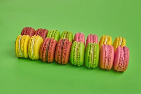 Colored macaron or macaroon, sweet meringue-based confection on green background Fotos Stock