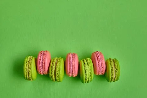 Colored macaron or macaroon, sweet meringue-based confection on green background Fotos Stock