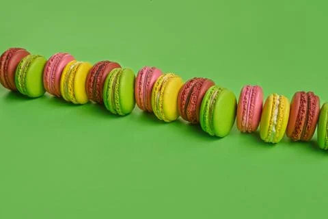 Colored macaron or macaroon, sweet meringue-based confection on green background Fotos Stock