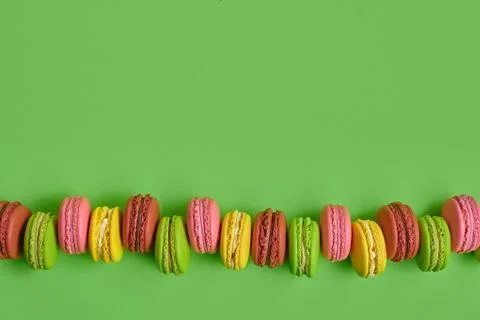 Colored macaron or macaroon, sweet meringue-based confection on green background Fotos Stock