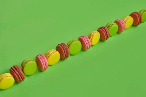 Colored macaron or macaroon, sweet meringue-based confection on green background Fotos Stock