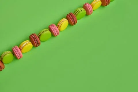 Colored macaron or macaroon, sweet meringue-based confection on green background Fotos Stock