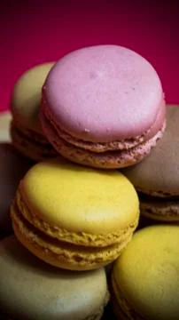 Colored macarons isolated on red background, typical French dish Stock Photos