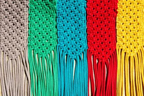 Colored macrame stripes in blue, yellow, red, beige, green and pink colors. Stock Photos