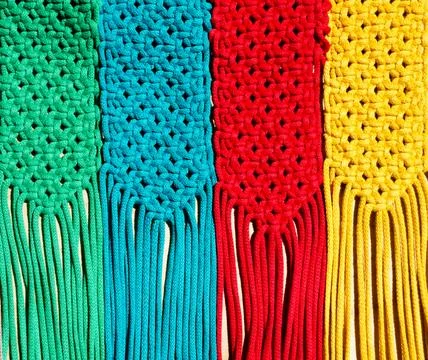 Colored macrame stripes in blue, yellow, red, beige, green and pink colors. Stock Photos