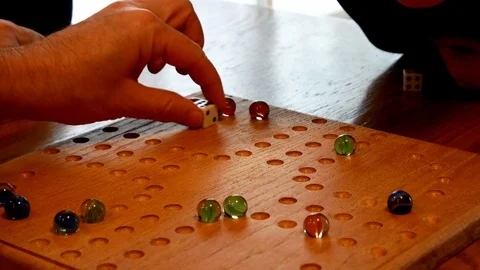 Colored marbles and dice are used to play a family game on a homemade board. Stock Footage 105687682