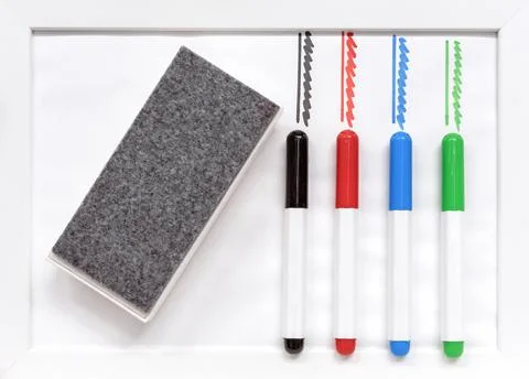 Colored markers and erasing sponge on a white board. Stock Photos