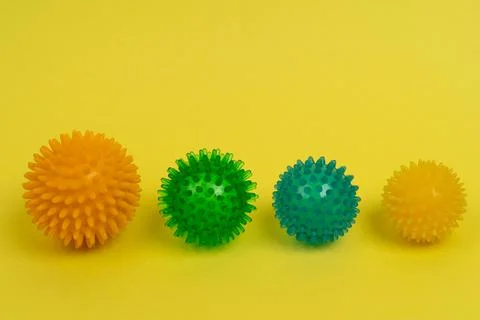 Colored massage needle balls of different sizes on a yellow background, the Stock Photos