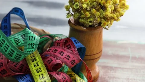 Colored measuring tapes in a wicker basket with yellow flowers Video stock 172245331