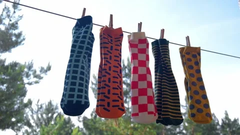 Colored men's socks with bright patterns are dried on a rope with clothespins. Video stock 196980208