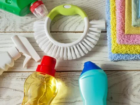 Colored microfiber napkins, cleaning agent, spray and brush on white floor. Stock Photos