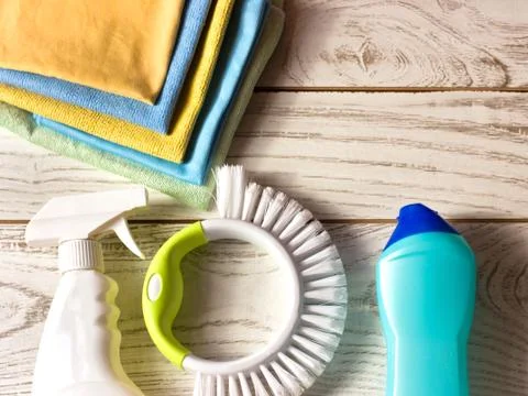 Colored microfiber napkins, cleaning agent, spray and brush on white floor. Stock Photos