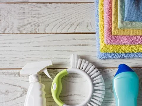 Colored microfiber napkins, cleaning agent, spray and brush on white floor. Stock Photos