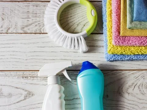 Colored microfiber napkins, cleaning agent, spray and brush on white floor. Stock Photos