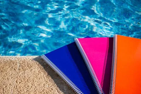 Colored notebooks next to a pool Stock Photos