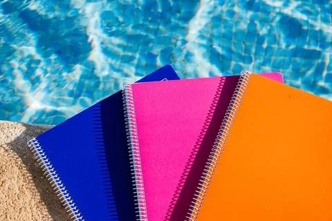 Colored notebooks next to a pool Stock Photos