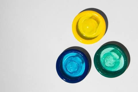 Colored open condoms on a light gray background. View from above. Stock Photos
