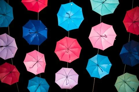 Colored open umbrellas on dark background. Stock Photos