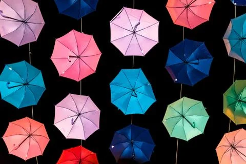 Colored open umbrellas on dark background. Stock Photos