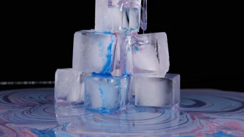 Colored paint spreads over the surface of the ice cubes and flows down onto the Stock Footage 205094700