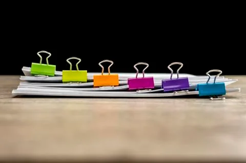 Colored paper binders on banch of paperwork Stock Photos