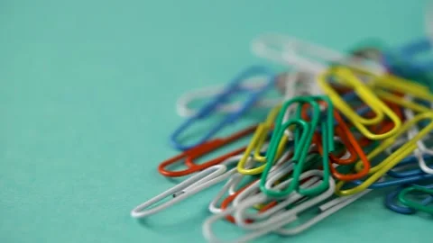 Colored paper clips fall on the blue  table. school supplies Stock Footage 140198276