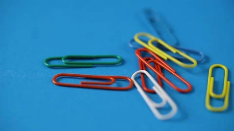 Colored paper clips fall on the blue table. school supplies. Stock Footage 141244044