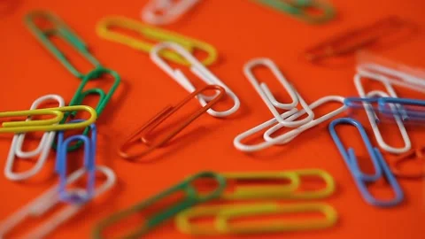 Colored paper clips fall on the orange table. school supplies. Stock Footage 140198287