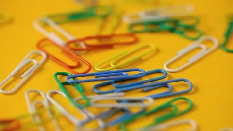 Colored paper clips fall on the yellow  table. school supplies. Stock Footage 141244045