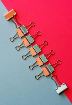 Colored paper clips on two backgrounds in half-pink and blue. Stationery. Stock Photos