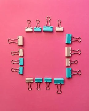 Colored paper clips on two backgrounds in half-pink and blue. Stationery. Stock Photos