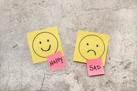 Colored paper notes with sad and happy drawing faces and single words Stock Photos