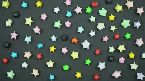 Colored paper stars appear on a black backgroun. Stop motion Stock Footage 242534223