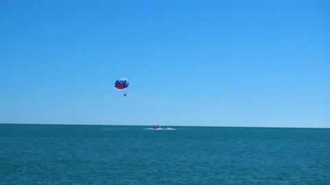A colored parachute hovers in the sky attached to the boat Stock-Footage 90247993