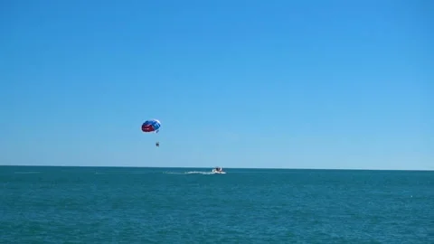 A colored parachute hovers in the sky attached to the boat Video stock 90248022